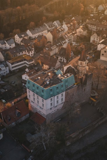 Aerial view of a village with a castle in warm evening light surrounded by trees, Dillweisenstein,