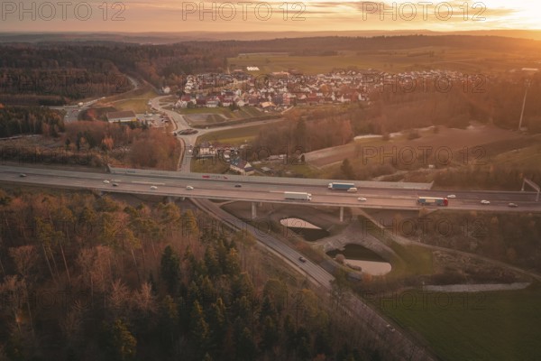 Sunset over a rural village with a motorway leading through fields and forests, A8 motorway,