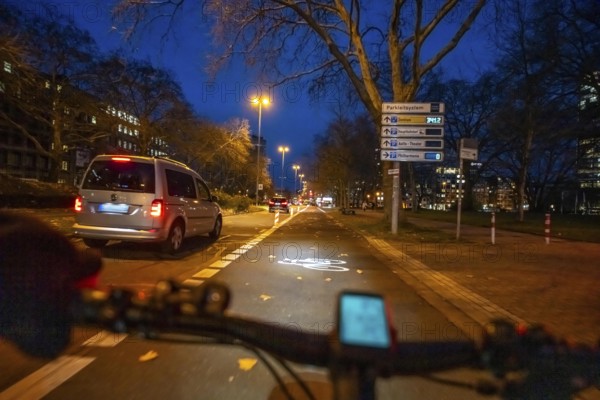 Cycling in the city, in the dark, in the evening, cycling on a bike lane, Huyssenallee, in front of