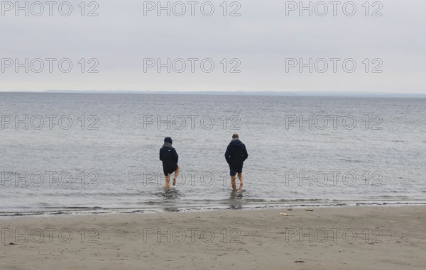 A couple standing barefoot in the cold seawater of the Baltic Sea, Scharbeutz, 28.11.2025,