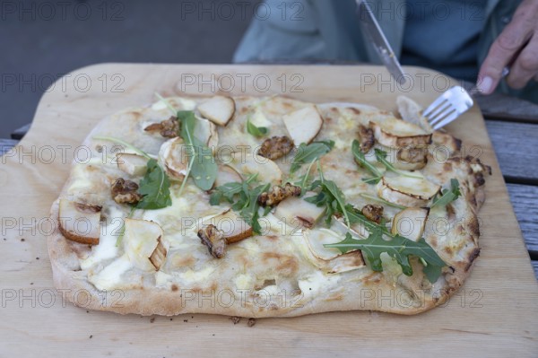 Flammkuchen with goat cheese, pears and nuts served on a wooden board, Ahrenshoop, DarÃŸ,