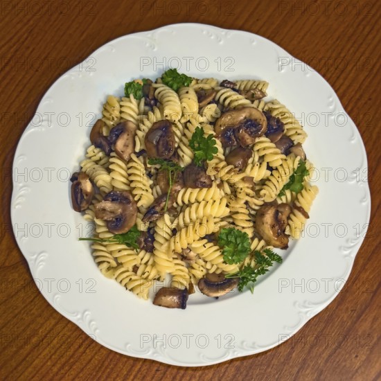Simple Italian dish pasta fusilli with mushrooms garnished with parsley, vegan cuisine,