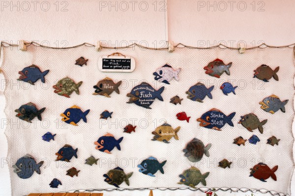 Maritime decoration, various wooden fish in a fishing net, funny signs, garden restaurant,