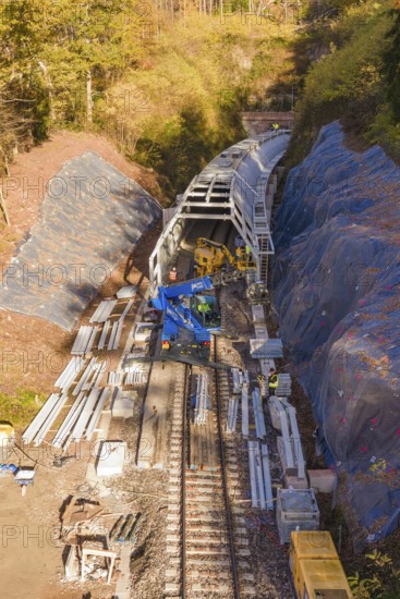 Aerial view of a construction site with railroad tracks and tunnel under construction, Hermann