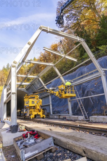 Construction work at a tunnel entrance in autumn with yellow construction equipment and visible