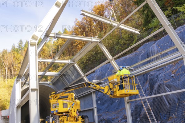 Workers on a lift building tunnel surrounded by colorful autumn trees, Hermann Hesse Railway bat