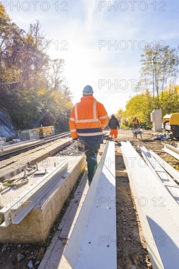 Construction workers in protective clothing walk along a construction site in an autumn scene,