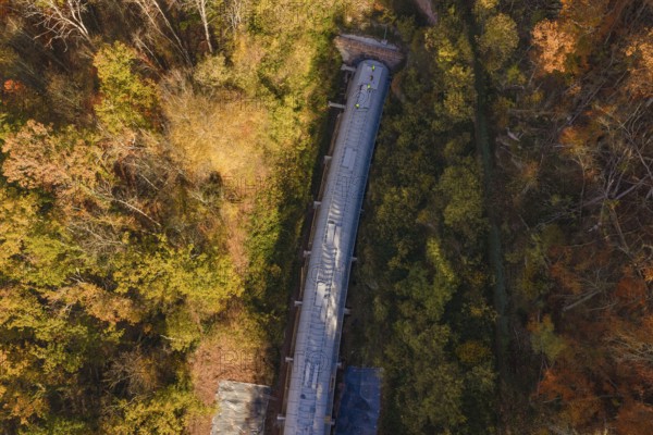 Autumn forest frames a tunnel construction project, shown in a colorful aerial view, Hermann Hesse