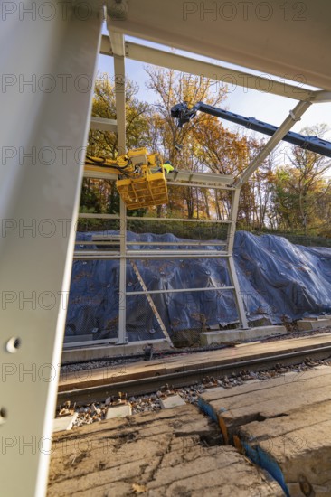 Metal frame construction with crane over tracks in an autumn environment with forest in the