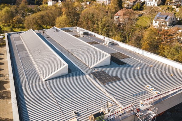 Detailed view of a modern building roof with solar cells, surrounded by trees, PV at Walther