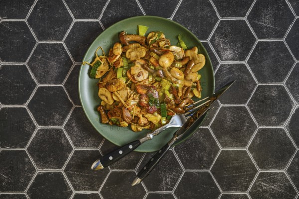 Mushroom stir fry is arranged on a green plate, featuring a mix of fried mushrooms and leek. The