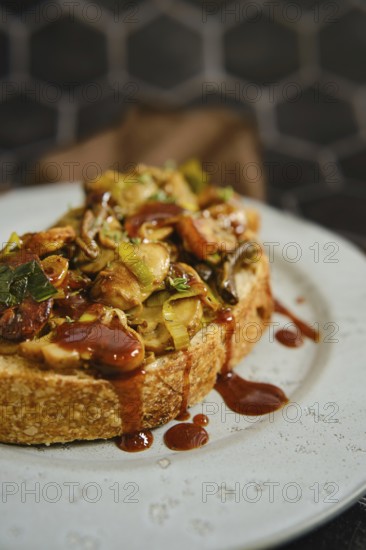 A warm mushroom sandwich is served on a rustic plate, topped with honey mushrooms, enoki mushrooms,