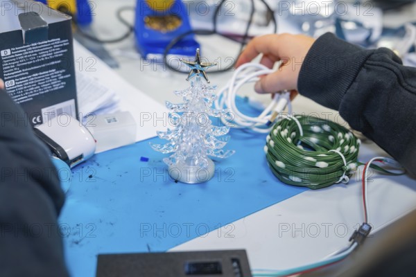 Craft table with small plastic Christmas tree and cables in hand, Jugend Forschungszentrum Nagold,