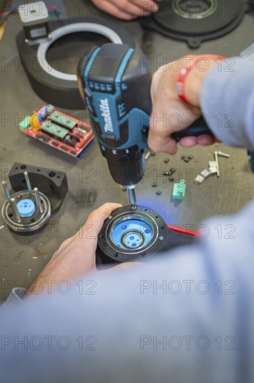 Person using a drill to assemble parts at a table, Jugend Forschungszentrum Nagold, Calw district,
