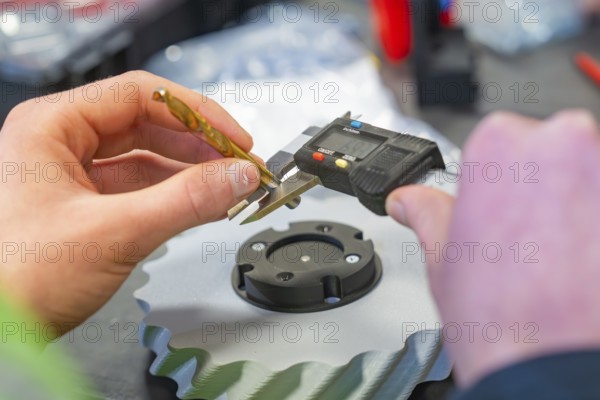 Hand holding caliper and measuring metal gear, Jugend Forschungszentrum Nagold, Calw district,