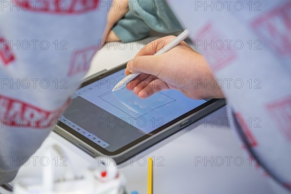 Person drawing with a stylus on a tablet surrounded by cool colors, Jugend Forschungszentrum