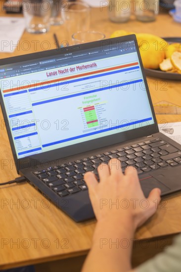 Hand operates a laptop with mathematics software on a wooden table, Jugend Forschungszentrum