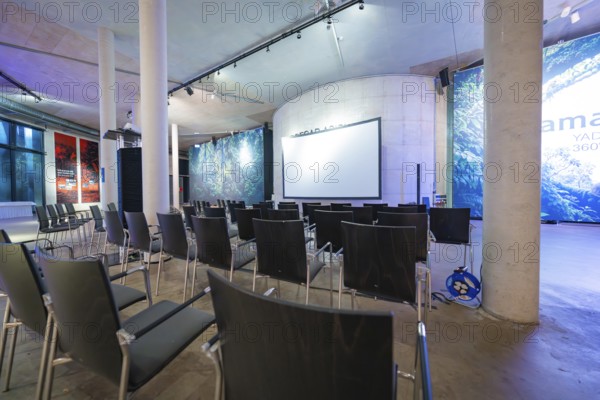 Empty conference room with chairs and a large projection screen under a high roof, Amazonia