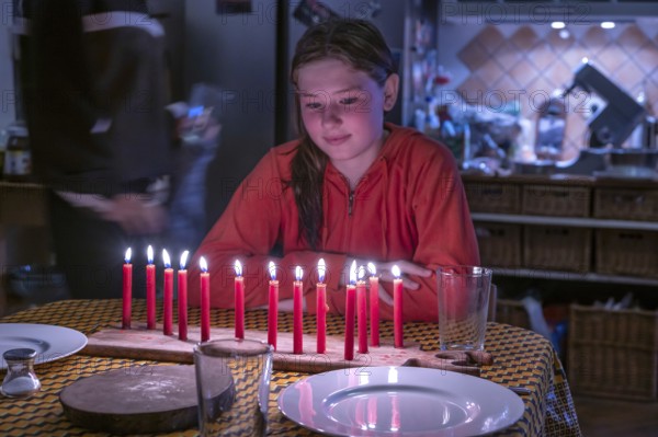 Young girl sitting at the table in front of her thirteen burning birthday candles, Othenstorf,