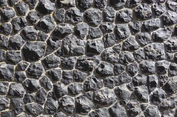 Close-up of a wall made of black textured stones