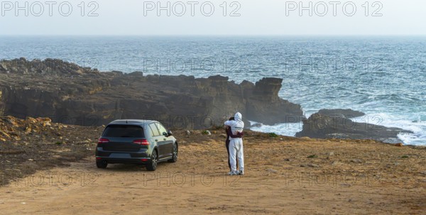 Young couple in love standing on the coast of Farol de Cabo Raso lighthouse, SÃ£o Bras de Sanxete