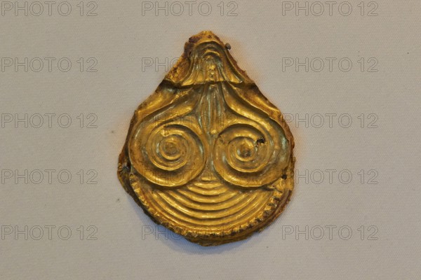 Golden ancient artifact with spiral pattern in teardrop shape, Archaeological Museum, Nemea,
