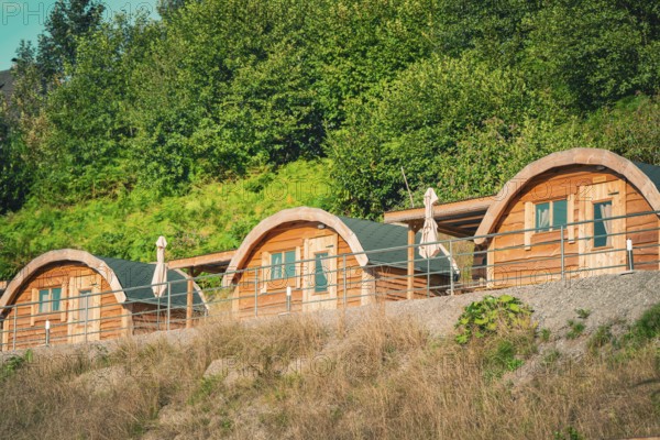 Three cozy wooden huts in a green setting give a feeling of relaxation