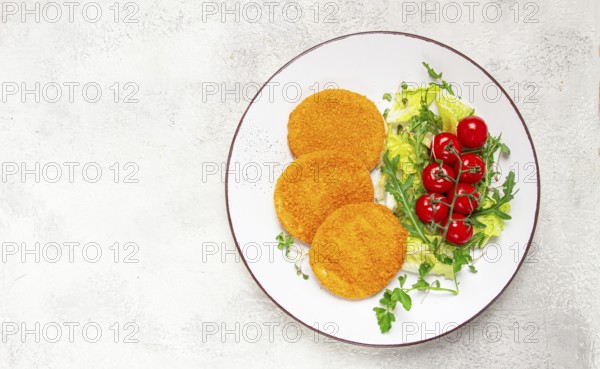 Crispy fried fish cutlets, fish burgers, on a white plate, with fresh lettuce leaves, arugula and