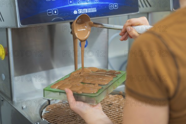 Chocolate is filled into flat molds by a person from a device, Christmas baking, Haselstaller Hof,