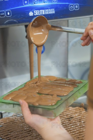 Hand pouring warm chocolate from a ladle into chocolate molds, Christmas baking, Haselstaller Hof,