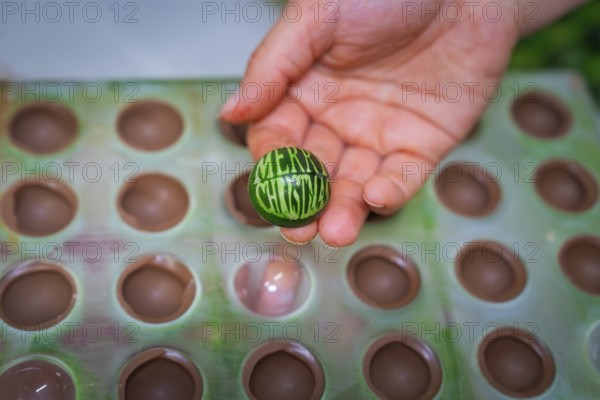 Hand holding green chocolate candy with Merry Christmas inscription out of a mold, Christmas