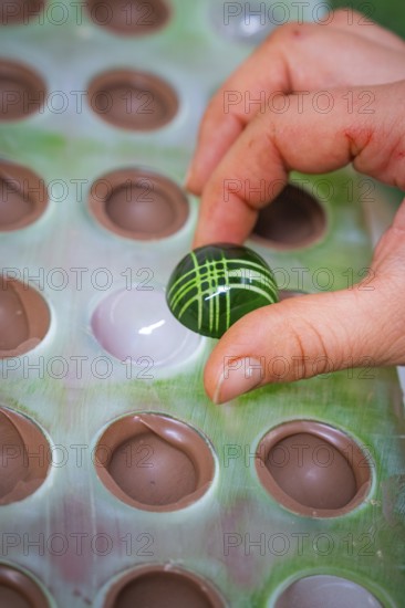 A green, artfully decorated ball is removed from a mold, Weihnachtsbacken, Haselstaller Hof,
