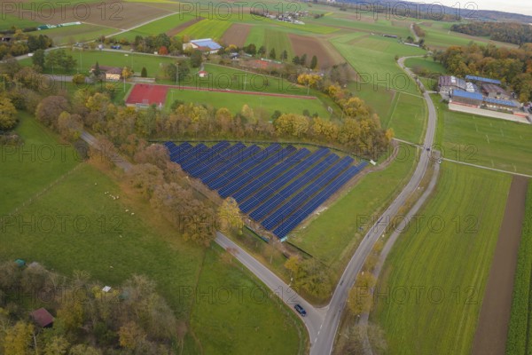 Solar system nestled in a green landscape with roads and fields in autumn, construction of PV