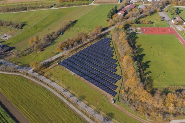 Aerial view of a solar system next to a soccer field in a rural autumn landscape, PV