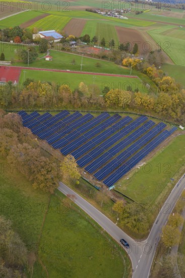 Solar systems embedded in fields and trees shown from the air during autumn, Bau PV