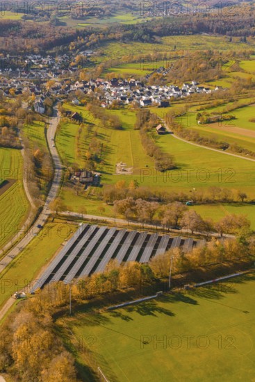 Large-scale solar plant in rural landscape near a village and roads, construction of a PV open-air