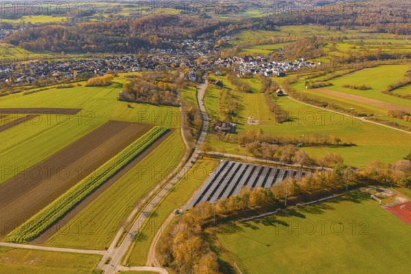 Autumn landscape with fields, forests and a small village viewed from the air, construction PV