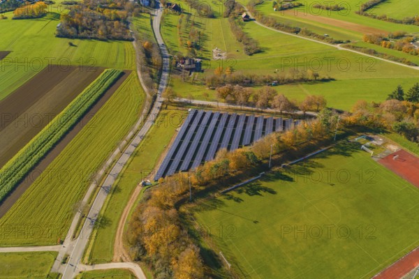 Landscape with solar panels and autumn trees surrounded by roads and fields, PV Freifaechenanlage