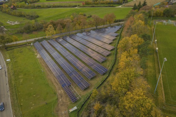 Solar system on a green area with autumn trees in the background, Bau PV Freifaechenanlage, Weil