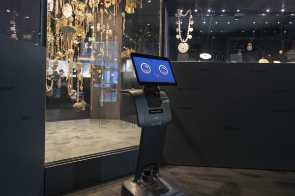 Smiling robot in front of display cabinet with jewelry in museum, robotic personality Roboloutions