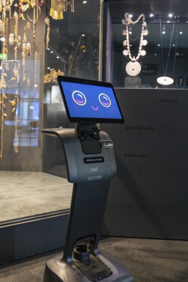 Robot with smiling display stands in front of a jewelry exhibition in the museum, robot personality