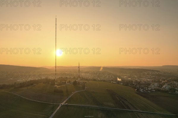 A sunset over countryside and fields with a distinctive transmission tower in the foreground,
