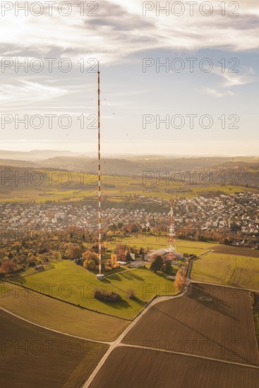 A tall radio tower rises above an autumn landscape with a small town in the background, MÃ¼hlacker,