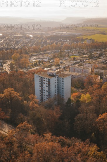 A high-rise residential building rises between autumn trees in an urban area, MÃ¼hlacker, Enzkreis,