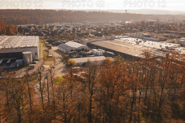 Industrial plant on the outskirts of town, surrounded by autumnal forest and light haze,