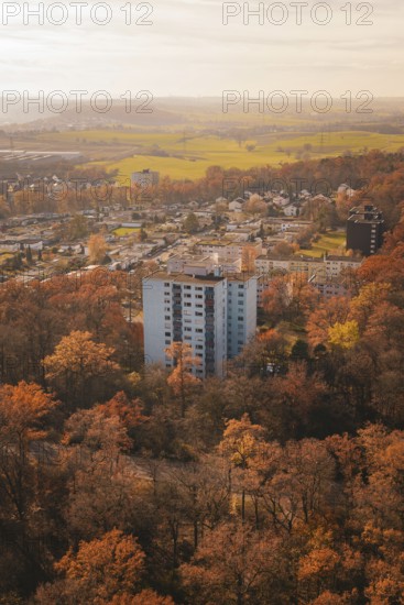 Block of flats surrounded by autumnal forest and fields close to the city in soft light,