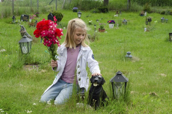 Grieving blonde 7-year-old girl at her dog's grave at pet cemetery in Ystad, SkÃ¥ne County, Sweden,