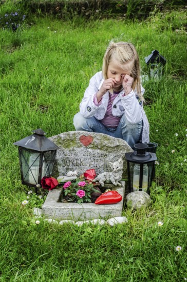 Grieving blonde 7-year-old girl at her cat's grave at pet cemetery in Ystad, SkÃ¥ne County, Sweden,