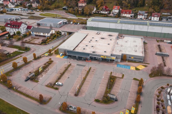 Large supermarket with adjacent parking lot and surrounding residential buildings in an autumn city