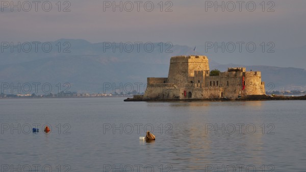 Bourtzi island fortress, tranquil water landscape with a historic castle and buoys in the evening